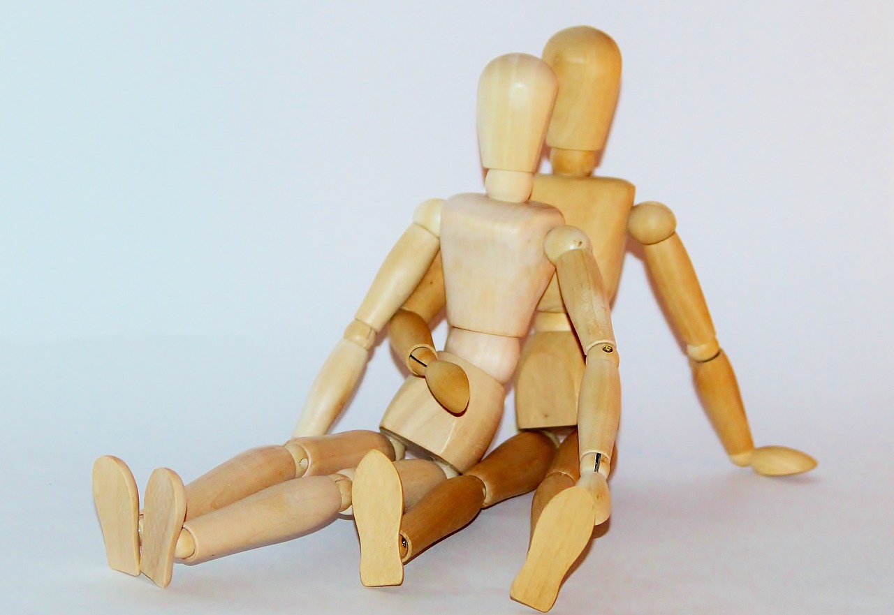 Dos muñecos articulados de madera abrazados como si fueran una pareja